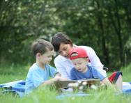 Mother and children reading outdoors