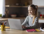 Girl typing on laptop - BigStock