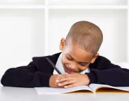 What is Look, Cover, Write, Check? Child happily writing in school book