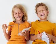 Two children laughing and writing
