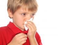 Boy sneezing and wiping nose