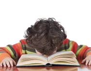 Tired boy reading at desk