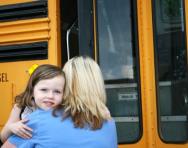 Mum hugging little girl goodbye at school bus