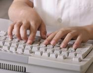 Child typing on a computer keyboard