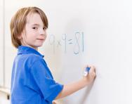 Child writing numbers on whiteboard