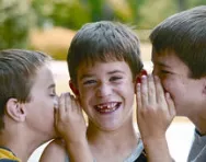 Children whispering in boy's ear Children whispering in boy's ear