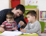 Dad doing homework with child and toddler