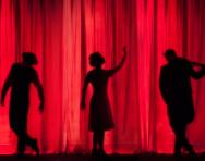 performers on stage with red curtain