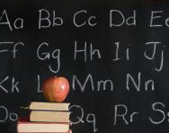 Alphabet on blackboard and apple on book