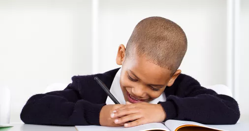 Child happily writing in school book