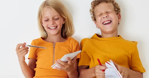 Two children laughing and writing
