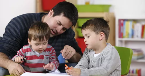 Dad doing homework with child and toddler