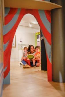 Parent and children reading books at the museum